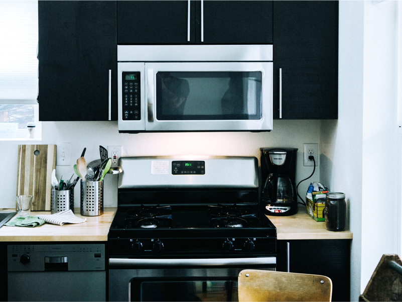 A microwave between black cabinets above a stove